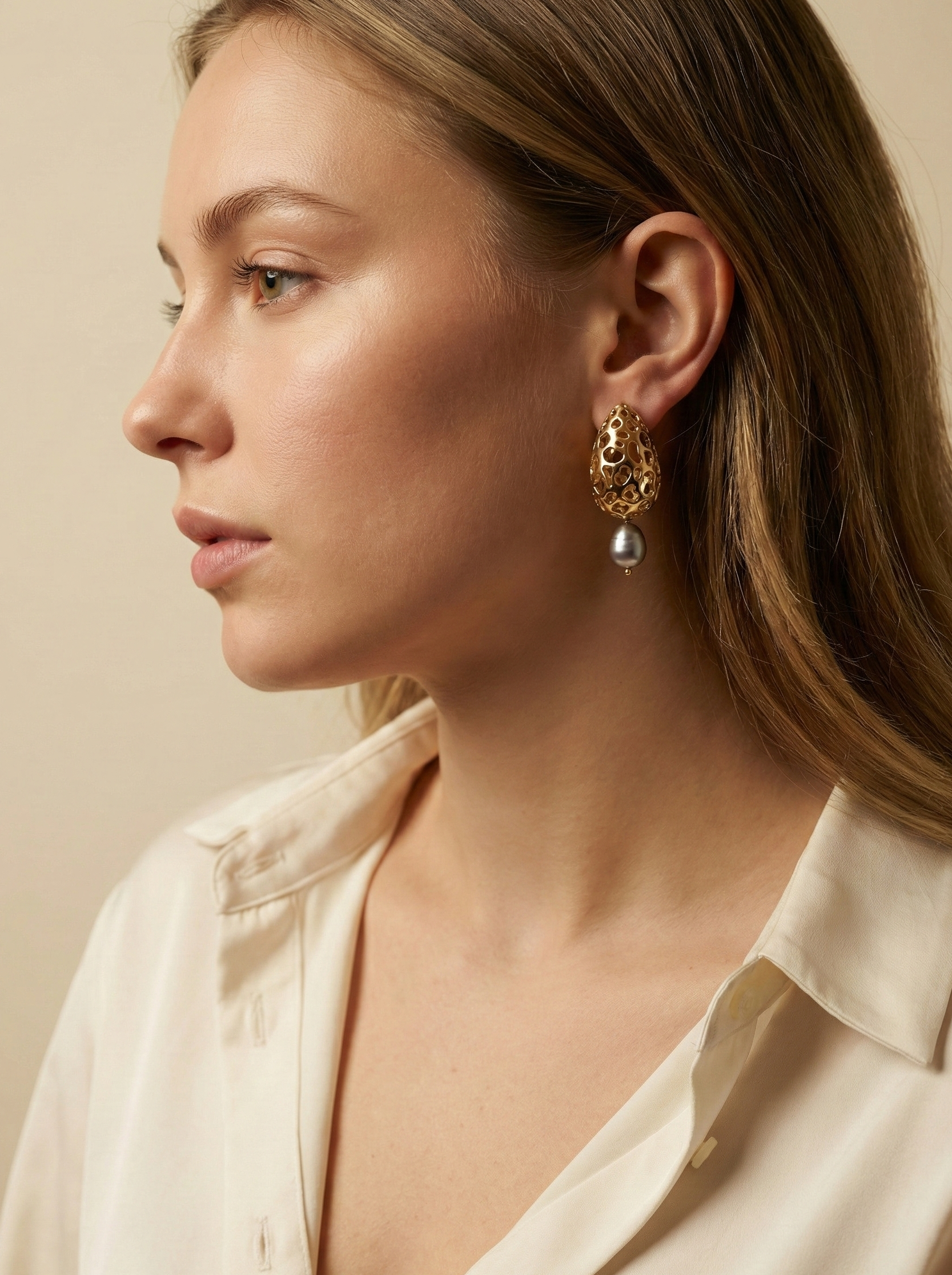 Close-up detail of luxury gold lattice teardrop earrings featuring a suspended metallic grey freshwater baroque pearl with high chrome luster
