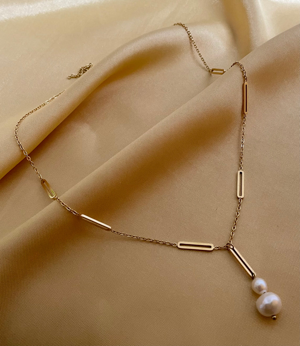 Elegant gold lariat style necklace with genuine freshwater baroque pearls. Minimalist bridal jewelry on a female model, highlighting high-luster pearl drop and modern gold link chain design