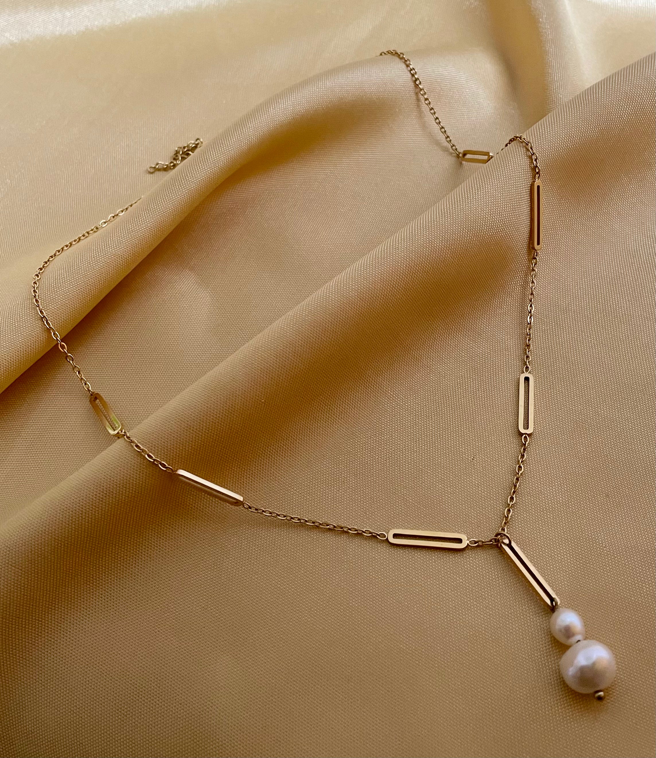 Elegant gold lariat style necklace with genuine freshwater baroque pearls. Minimalist bridal jewelry on a female model, highlighting high-luster pearl drop and modern gold link chain design
