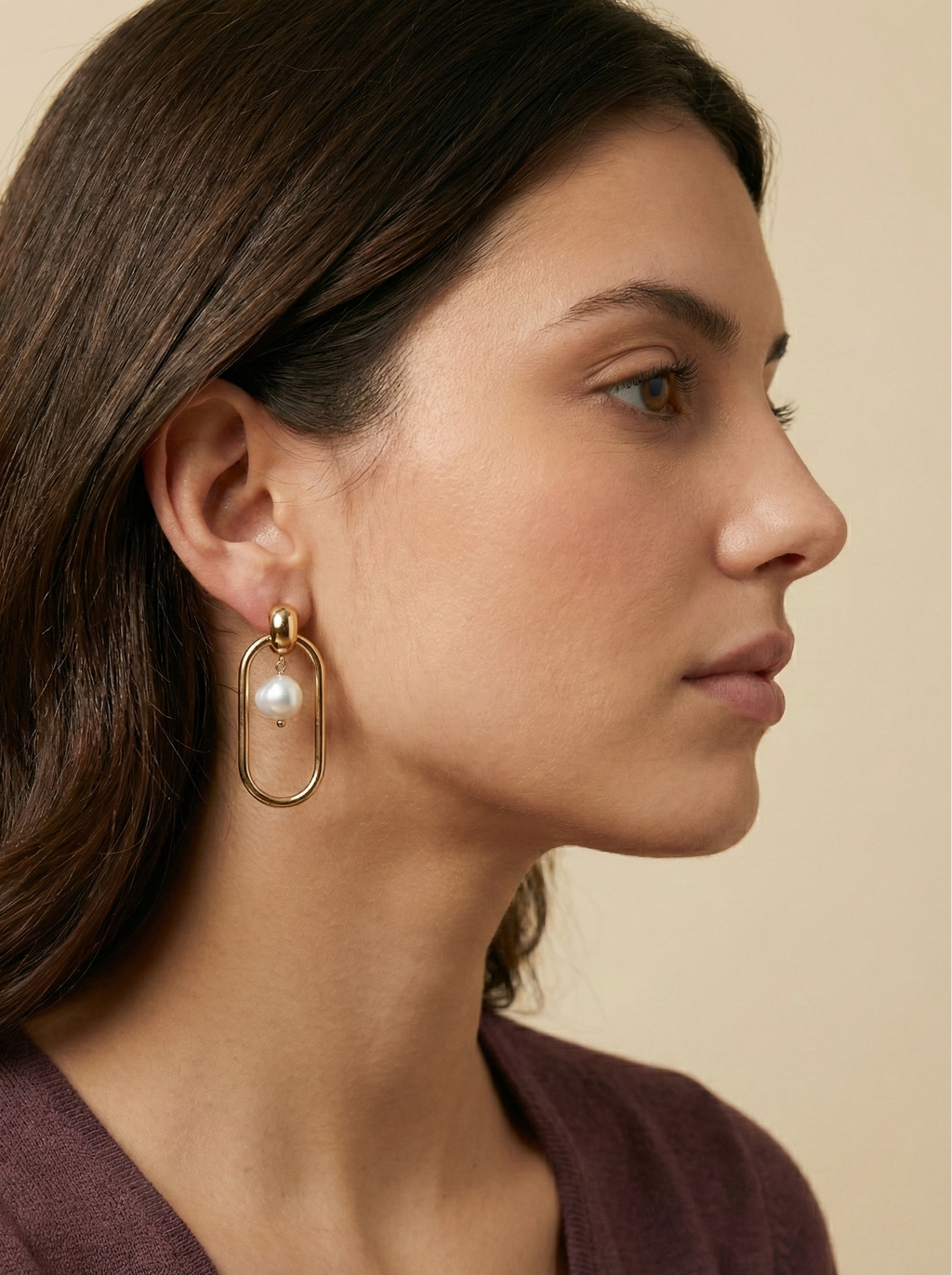 High-resolution detail of high-luster white pearl earrings set in a polished gold oval frame, highlighting the nacre texture and gold clasp quality