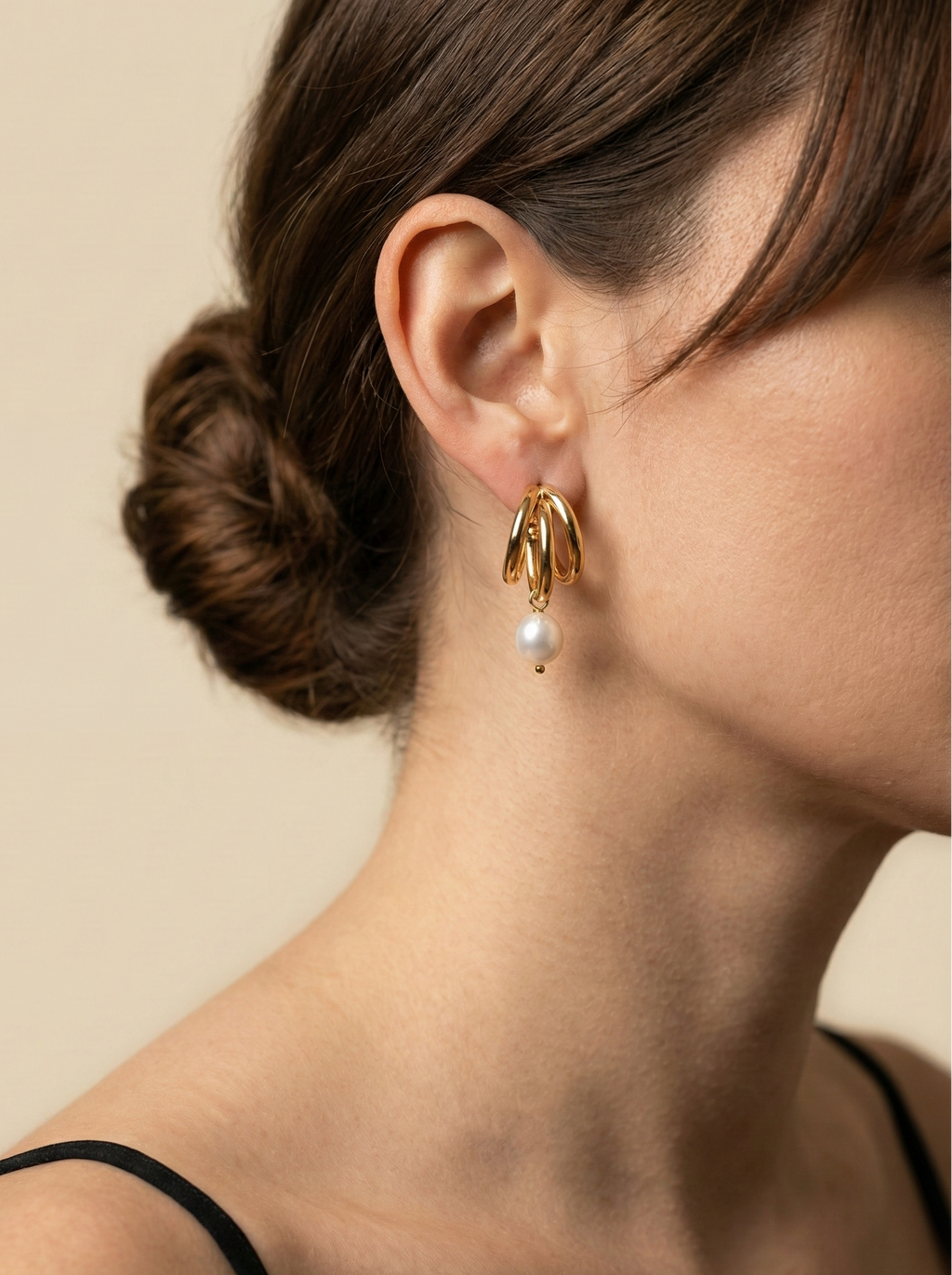 Model wearing chunky 18k gold split hoop earrings with white pearl dangles. Close-up side profile showing ear styling and jewelry scale