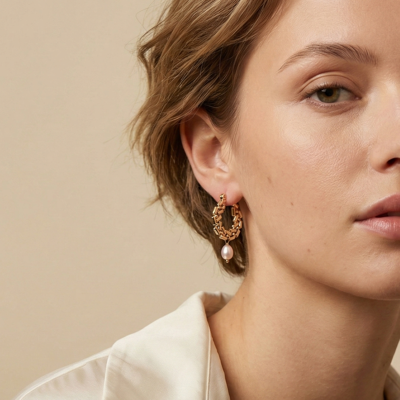 Woman wearing elegant Naya gold drop earrings with champagne pearls. Modern minimalist pearl jewelry styled for a sophisticated everyday or evening look.