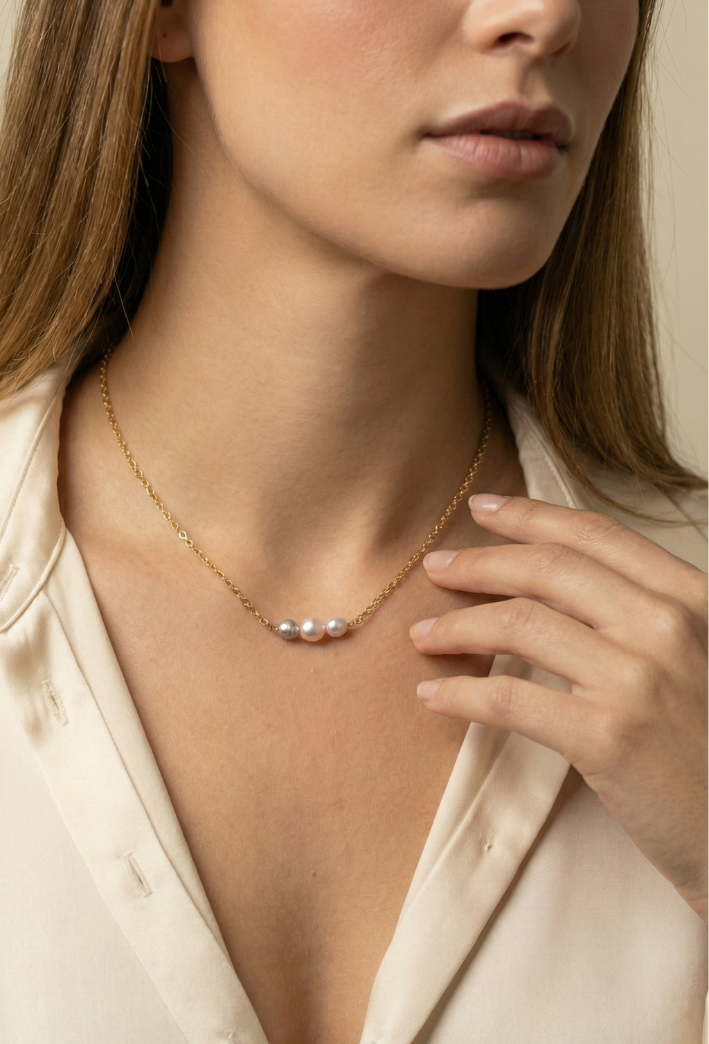 Delicate gold link chain necklace featuring a trio of pearls: a central oval pink pearl flanked by two smaller, irregular grey baroque pearls