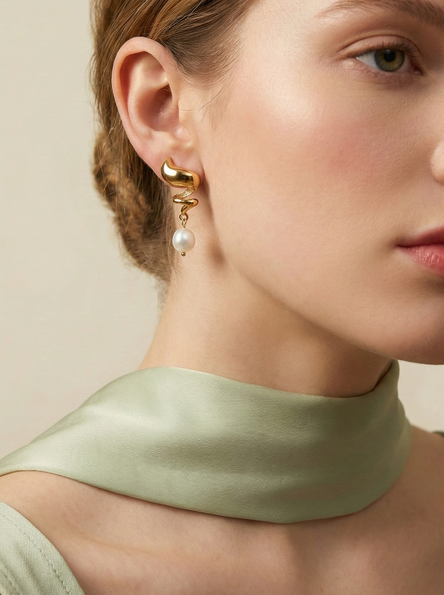 Woman wearing Alizee spiral gold drop earrings with white baroque pearls. Bohemian chic pearl jewelry styled for everyday elegance.