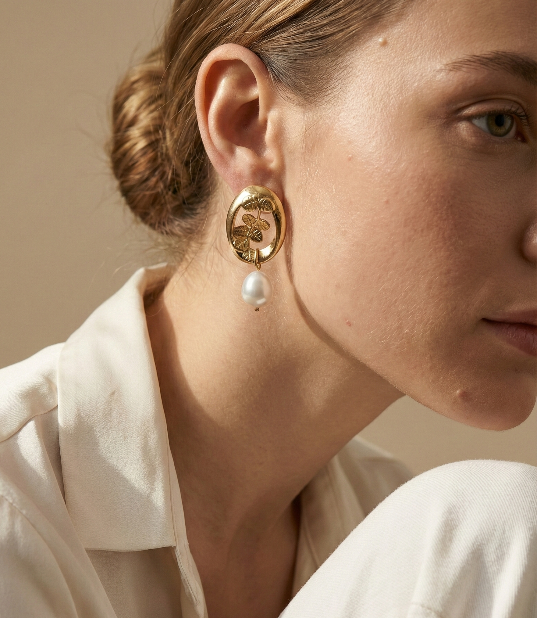 Close-up of a model wearing a vintage french style 18k gold earring with cultured pearl drop on a neutral background
