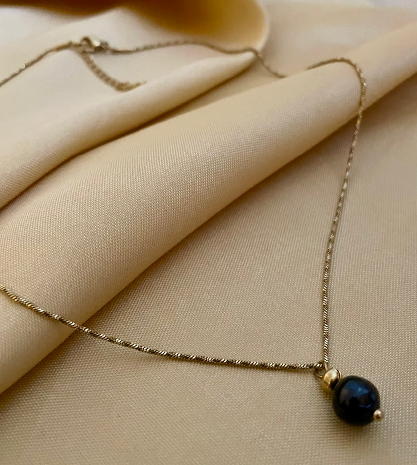 Elegant black pearl solitaire necklace on a twisted gold chain.