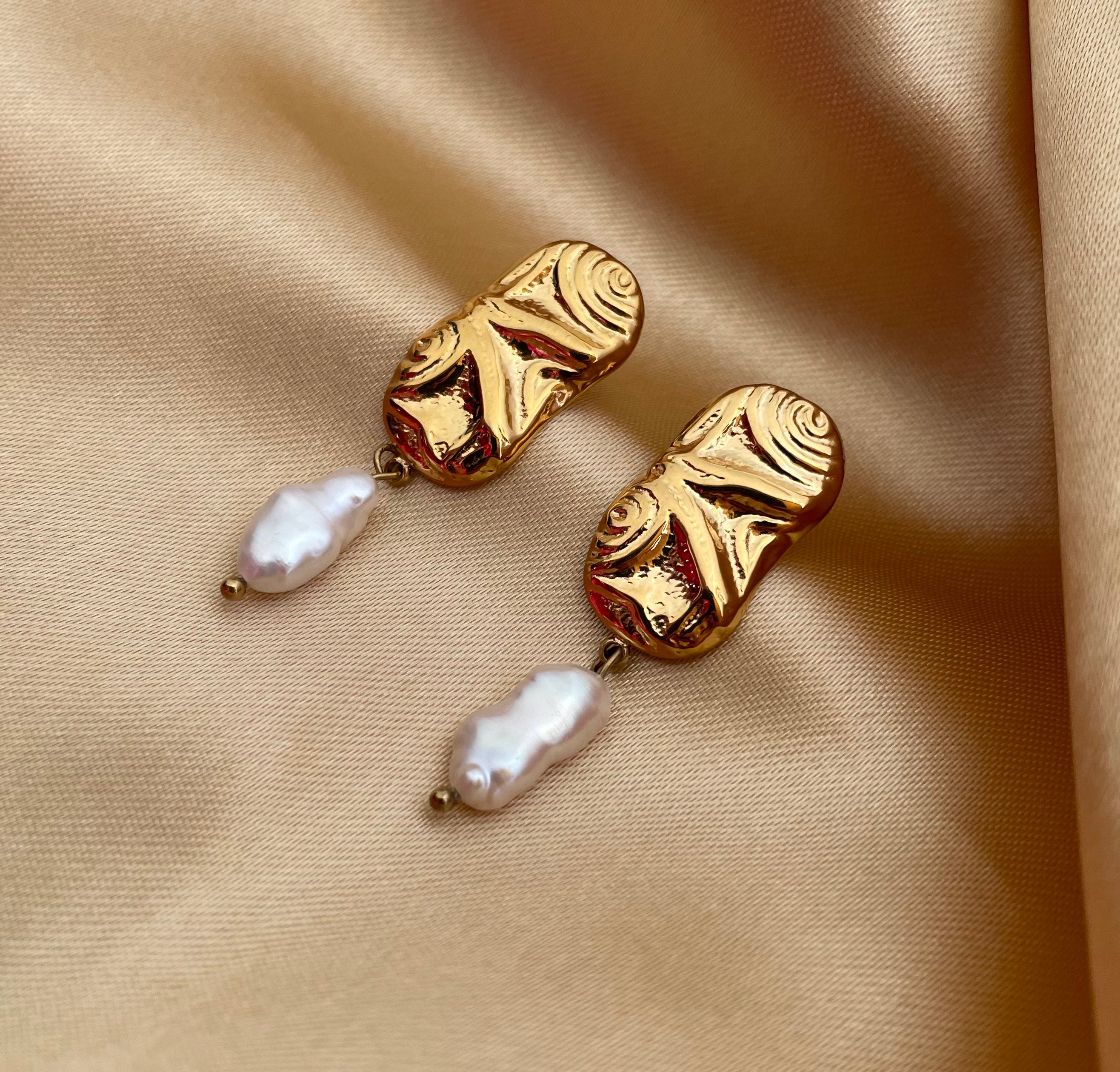Close-up of a sculptured aztec organic 18k gold earrings with japanese keshi pearls