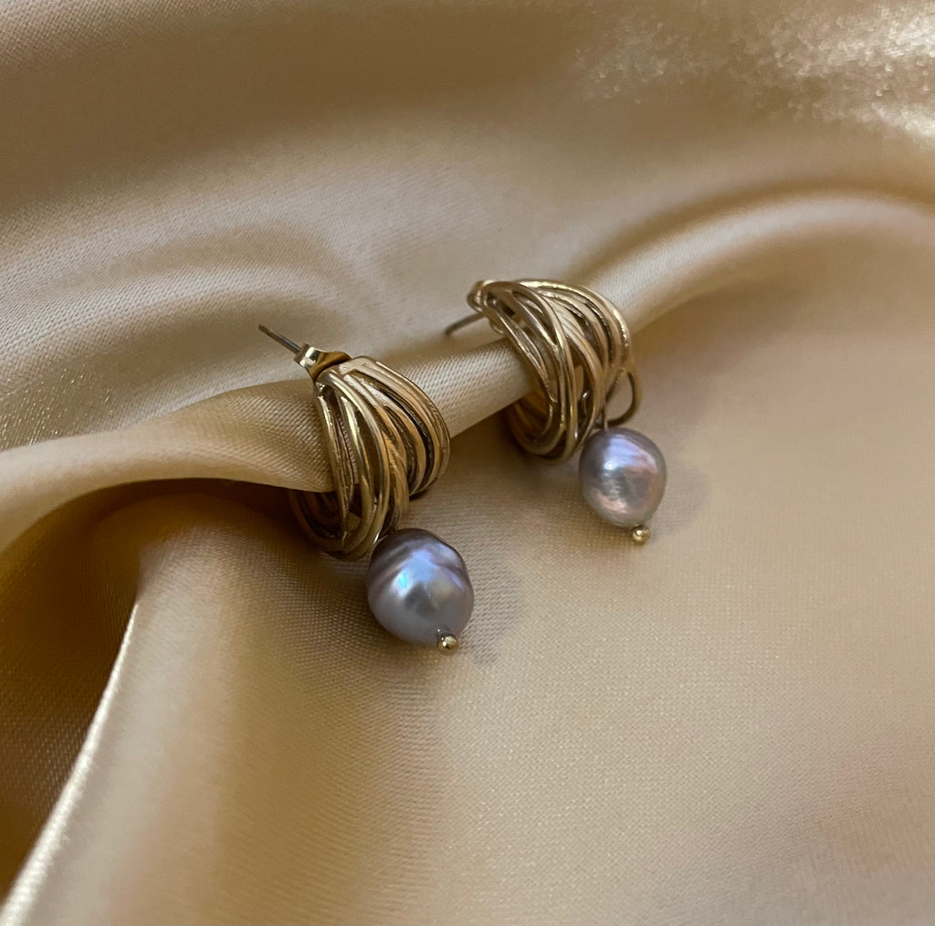 Editorial jewelry portrait showing an elegant grey pearl drop earrings with chunky gold hoops