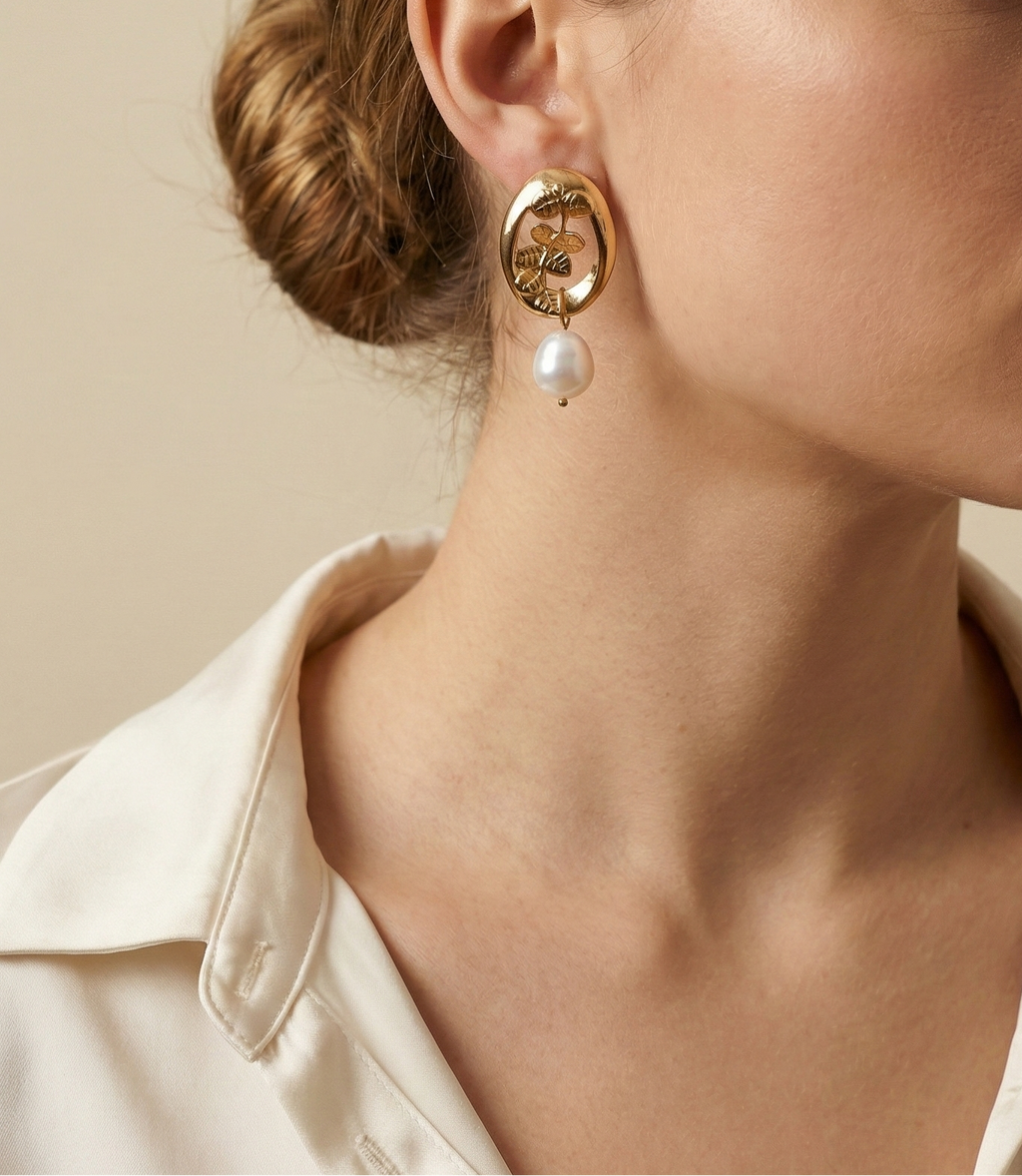 Close-up of a model wearing a vintage french style 18k gold earring with cultured pearl drop on a neutral background