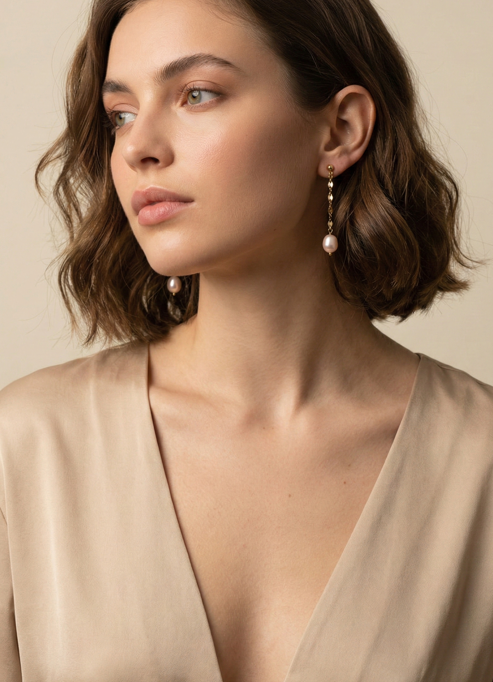 Woman wearing pearl earrings against a neutral background