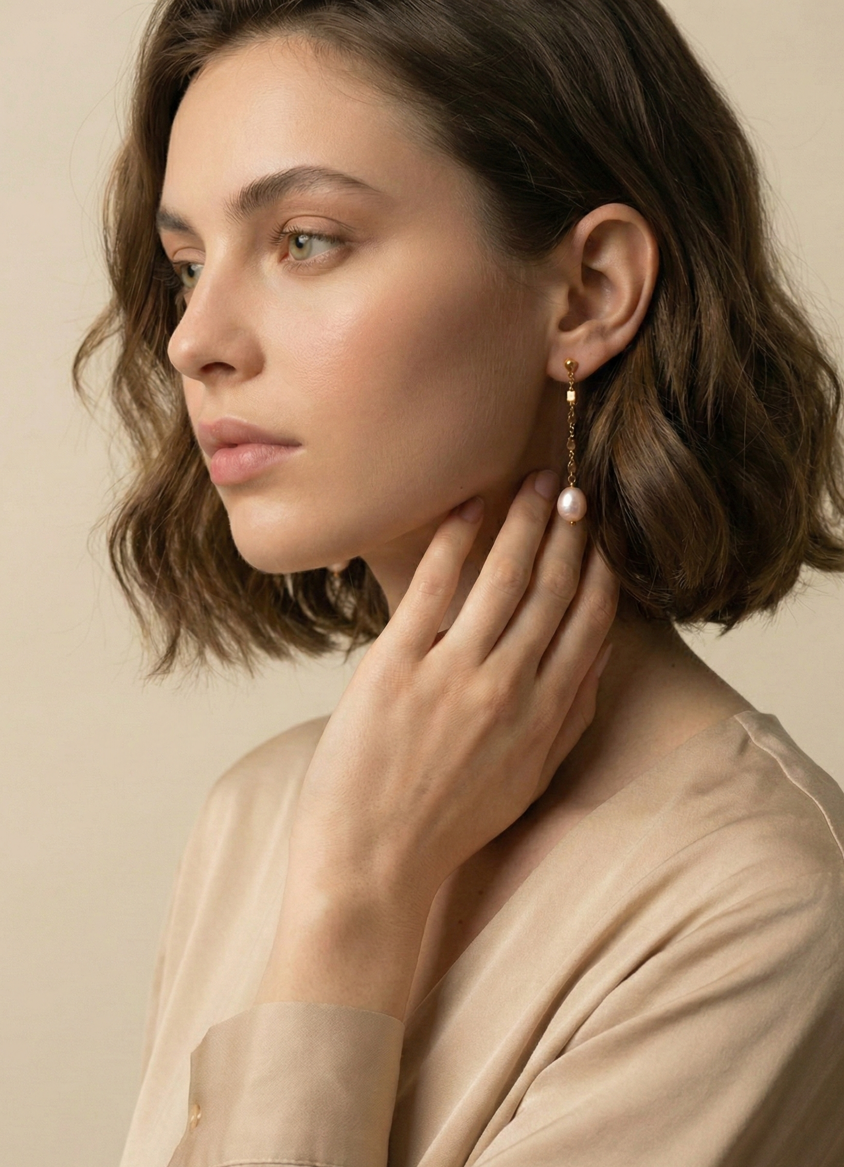 Woman wearing gold earrings with a neutral background
