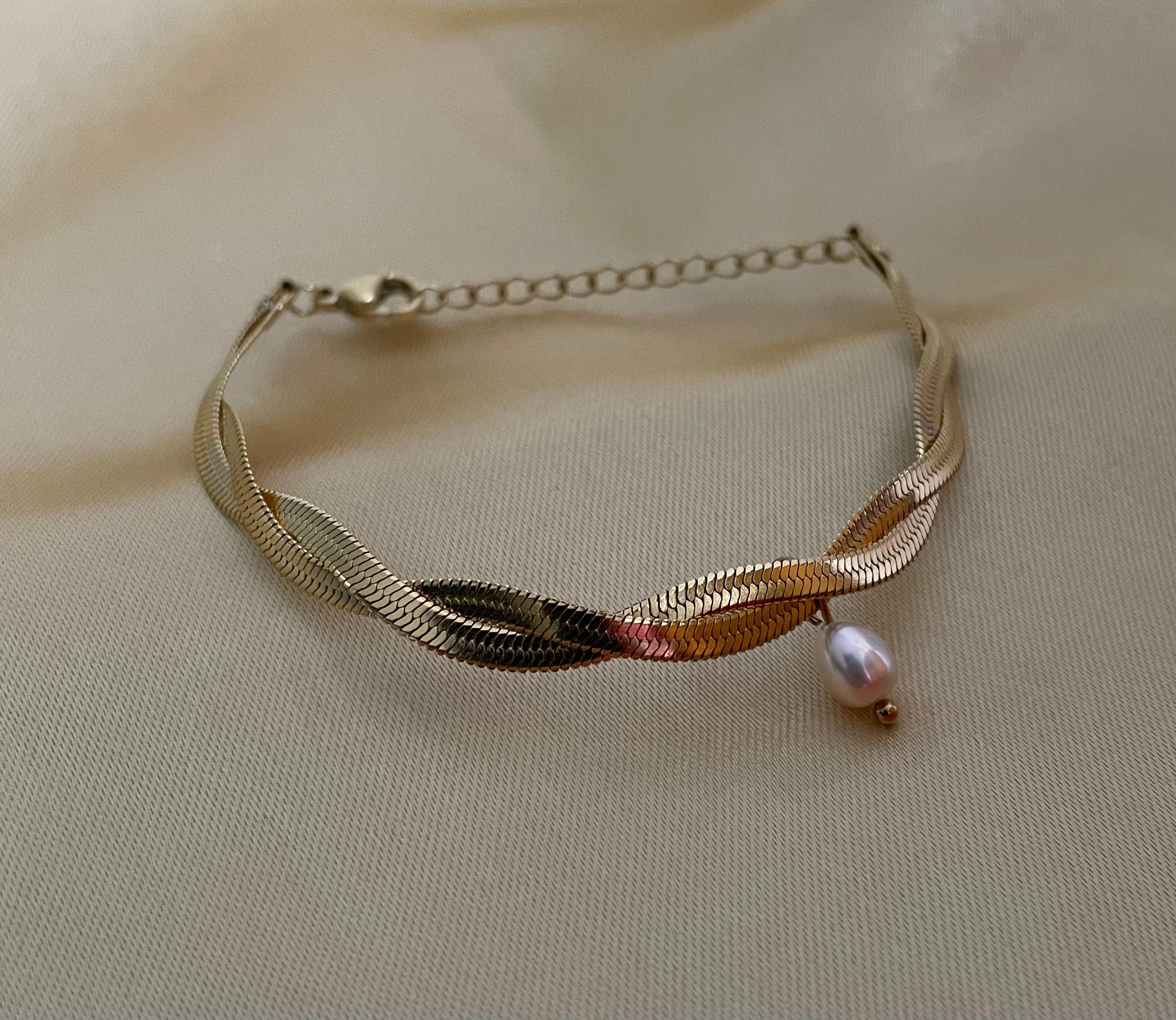 Bracelet with a pearl on a beige fabric background