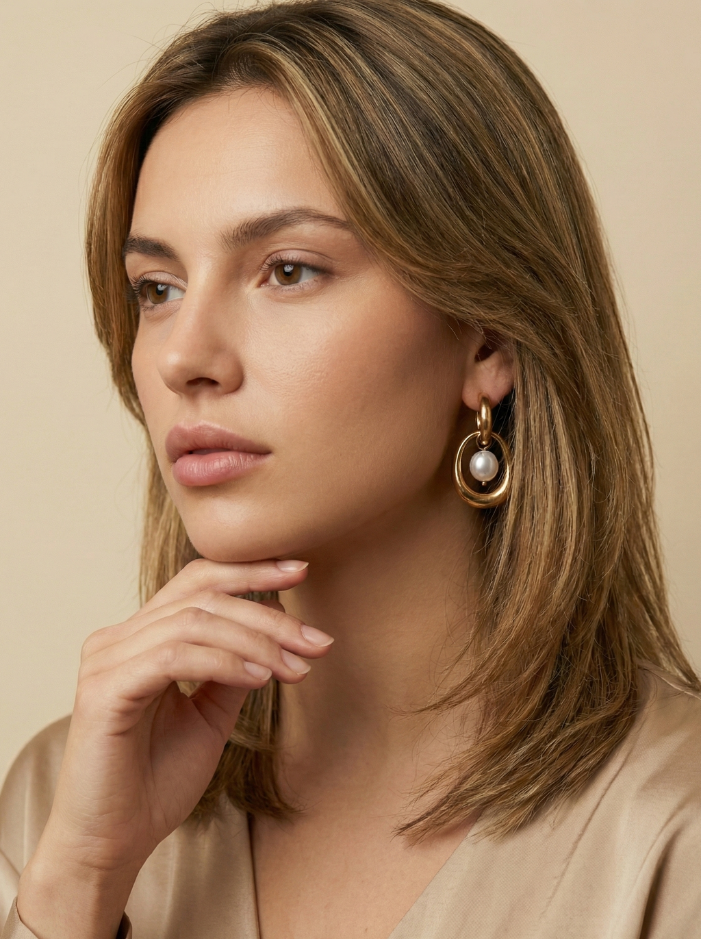 Close-up editorial photography of a gold hoop drop earring featuring a suspended organic white high-luster pearl. High-resolution luxury jewelry shot highlighting realistic gold texture and pearl iridescence.