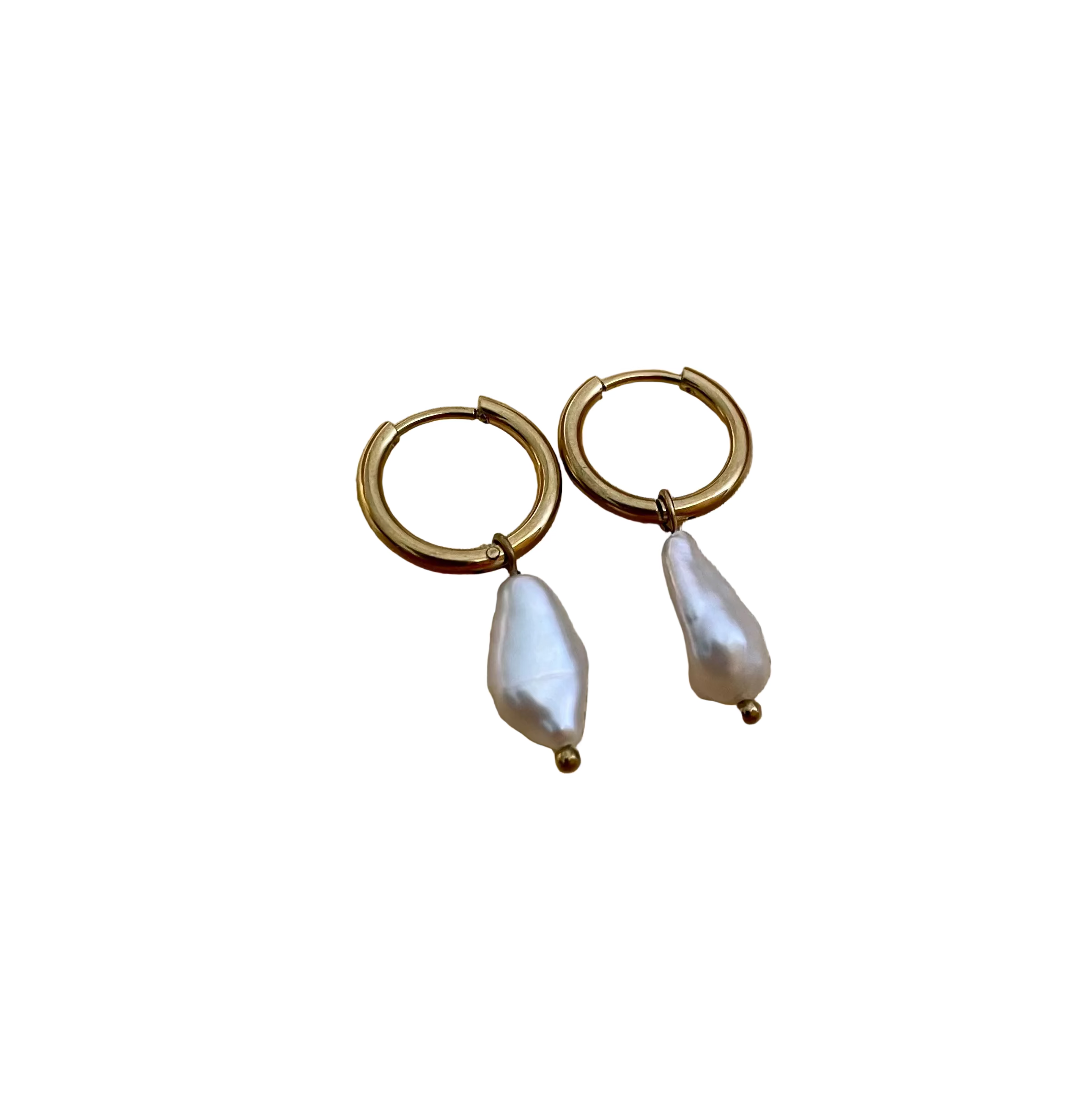 Close-up photography of a dainty gold hoop earring featuring a lustrous white baroque pearl drop worn on a model's ear. High-resolution commercial jewelry shot showcasing organic pearl texture, nacre iridescence, and a simple gold clasp against a matte ivory background.