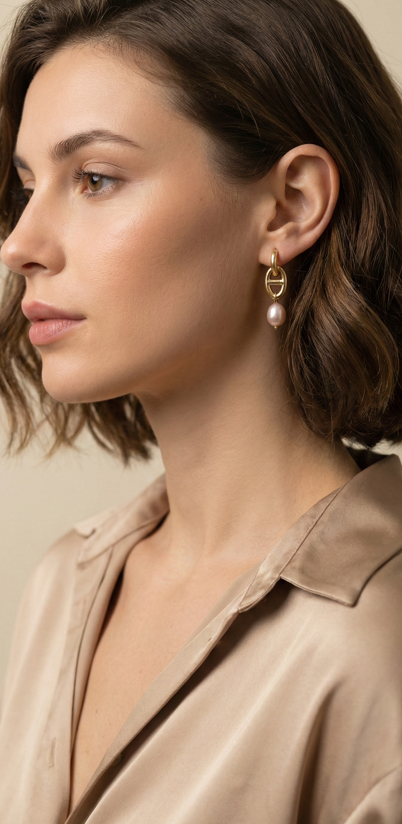 Woman wearing pearl earrings with a neutral background