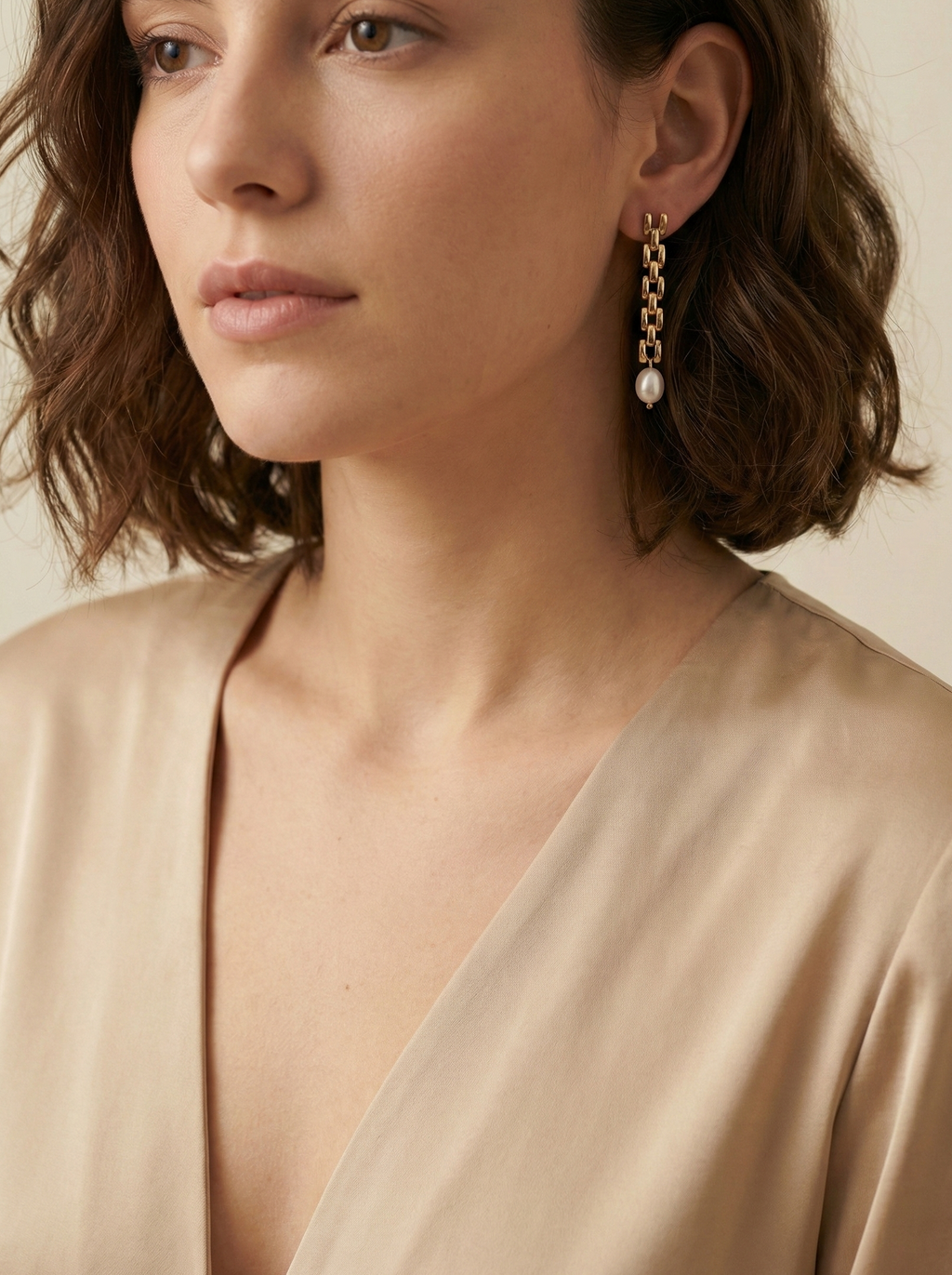 Gold rectangular link chain drop earrings featuring luminous white oval pearls on a beige silk background. Handcrafted Parisian pearl jewelry