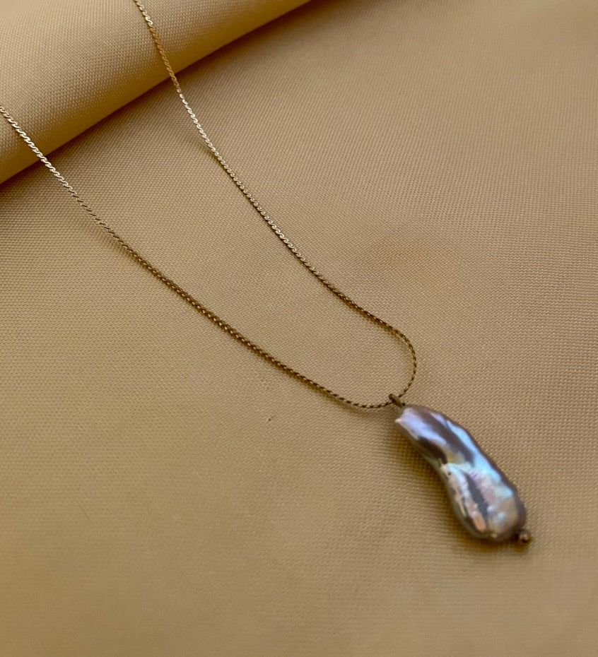Organic grey baroque pearl necklace featuring a high-luster Keshi pearl suspended on a fine gold chain. Minimalist jewelry styling