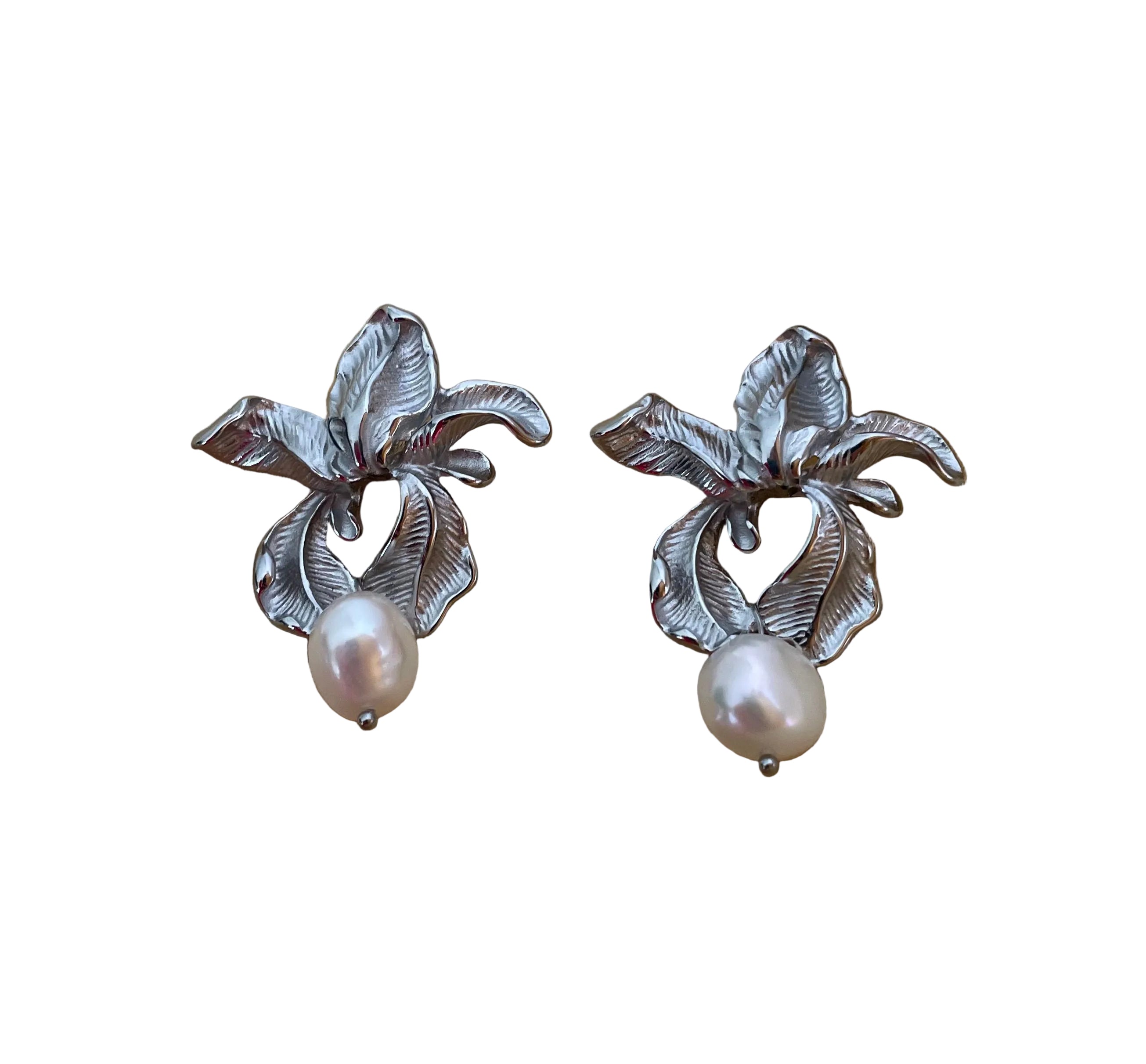 Macro detail showing the intricate textures of handcrafted silver flower earrings and the iridescence of the freshwater pearl attached