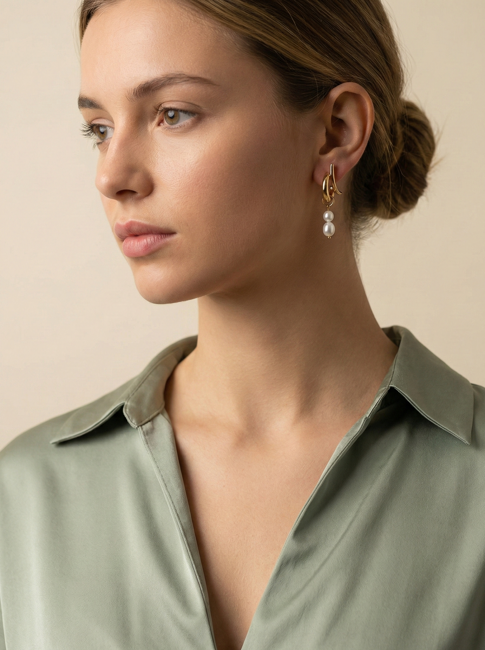 Modern gold pearl dangle earrings on ear; luxury bridal jewelry with high luster twin freshwater pearls and architectural gold design