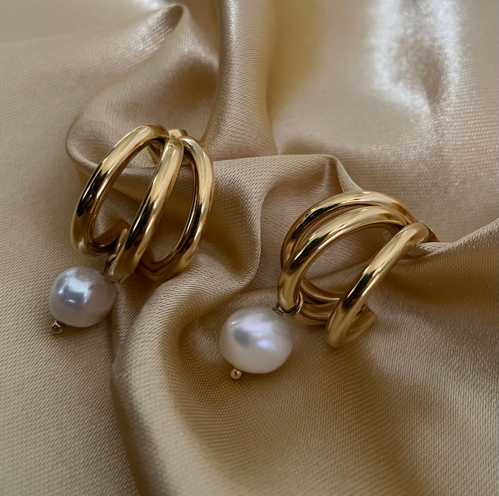 Model wearing chunky 18k gold split hoop earrings with white pearl dangles. Close-up side profile showing ear styling and jewelry scale