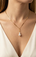 Elegant gold lariat style necklace with genuine freshwater baroque pearls. Minimalist bridal jewelry on a female model, highlighting high-luster pearl drop and modern gold link chain design