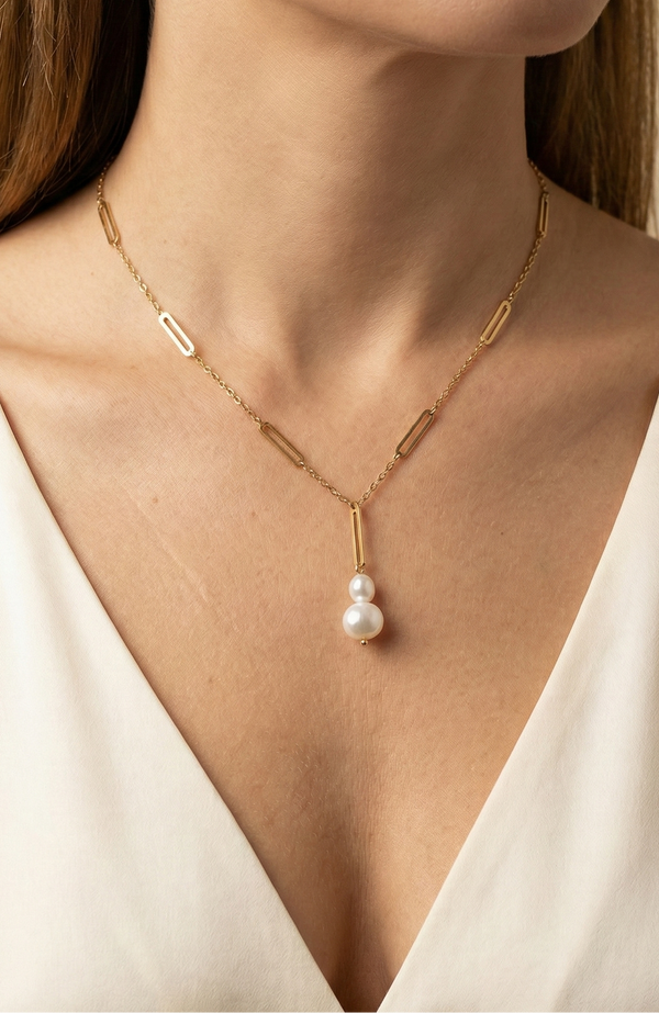 Elegant gold lariat style necklace with genuine freshwater baroque pearls. Minimalist bridal jewelry on a female model, highlighting high-luster pearl drop and modern gold link chain design