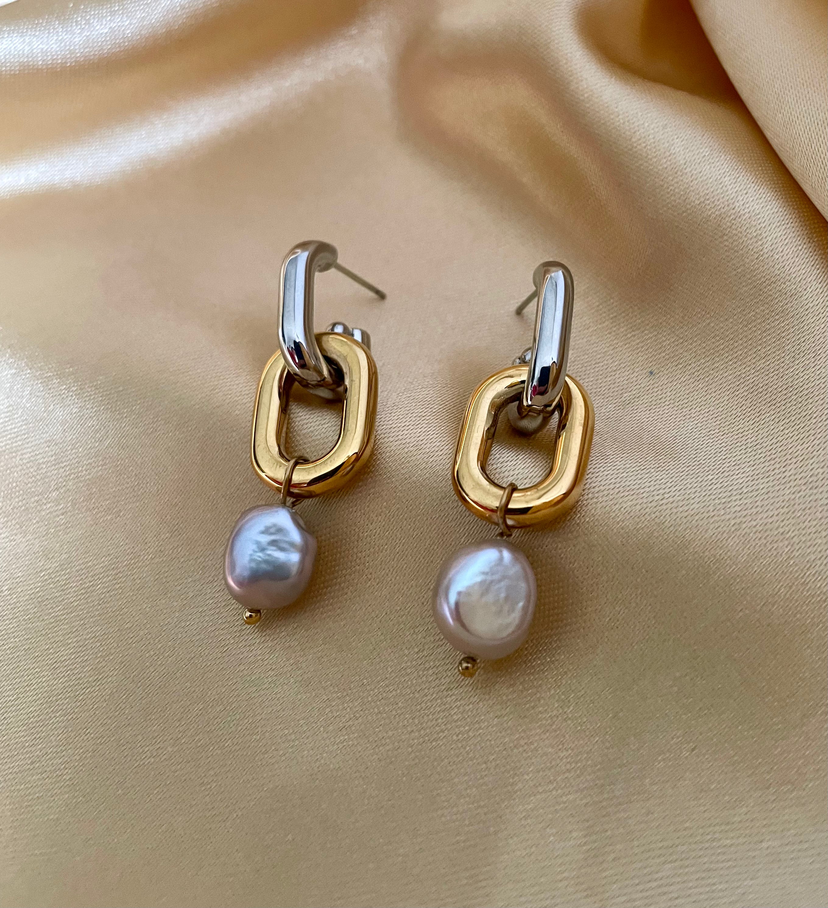 Close-up detail of mixed metal chain link earrings with grey pearl drops worn on the ear.