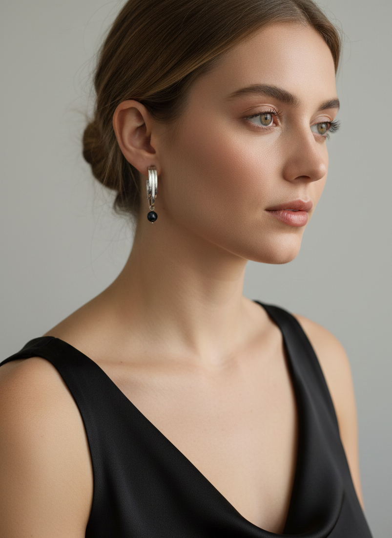 Woman wearing Naomi modern gold drop earrings with round black pearls. Elegant architectural jewelry styled for evening or professional wear