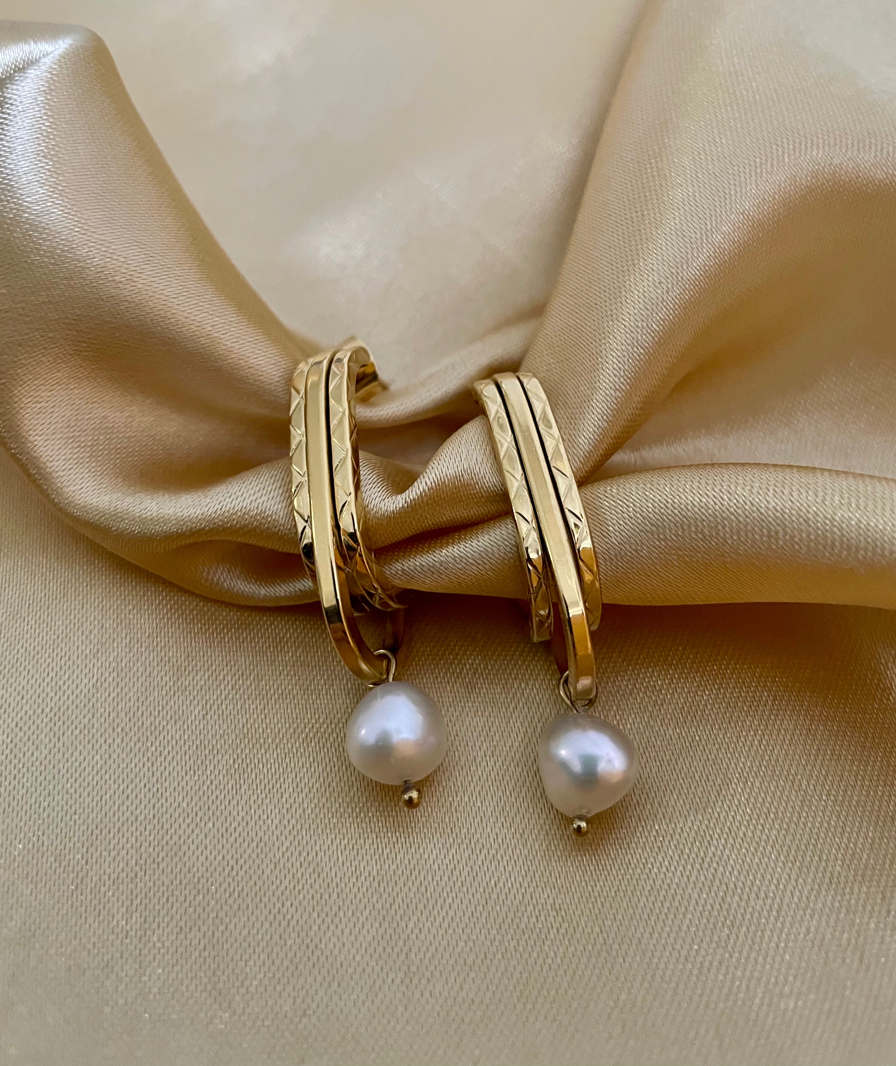 Woman wearing Naomi modern gold drop earrings with round white pearls. Elegant architectural jewelry styled for evening or professional wear