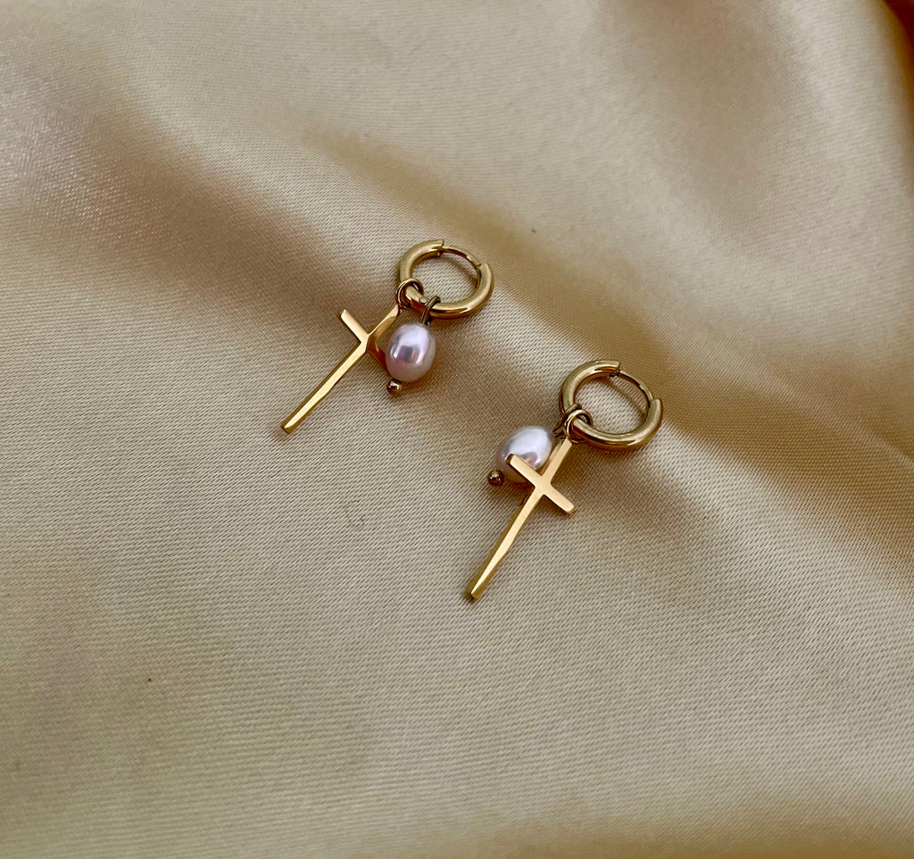 Close-up of a gold hoop earring with a pearl pendant.