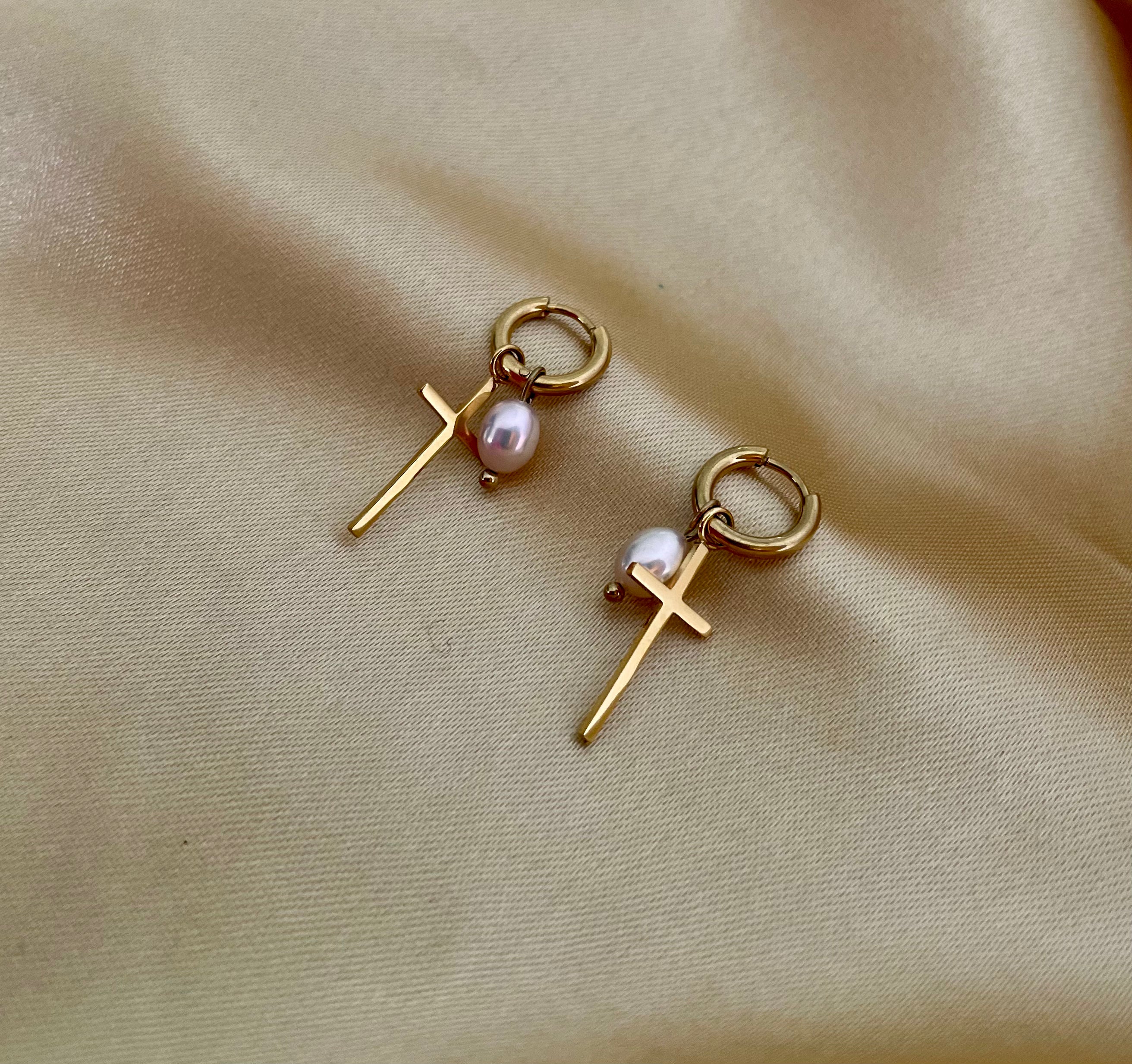Close-up of a gold hoop earring with a pearl pendant.