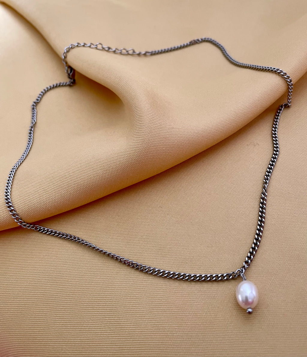 Necklace with a pearl pendant on beige fabric