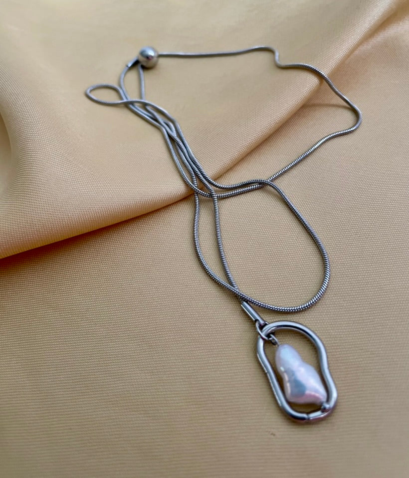 Necklace with a keshi pearl pendant on a beige fabric background