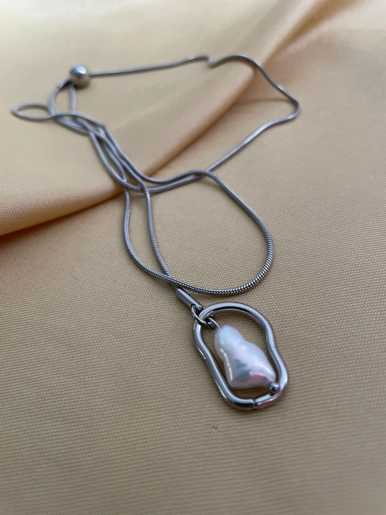 Silver necklace with a pendant on a beige fabric background