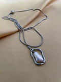 Silver necklace with a pendant on a beige fabric background