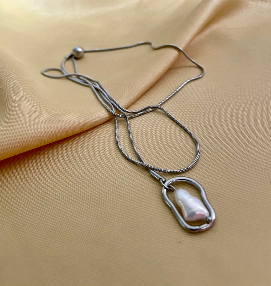 Silver necklace with a pendant on a beige fabric background